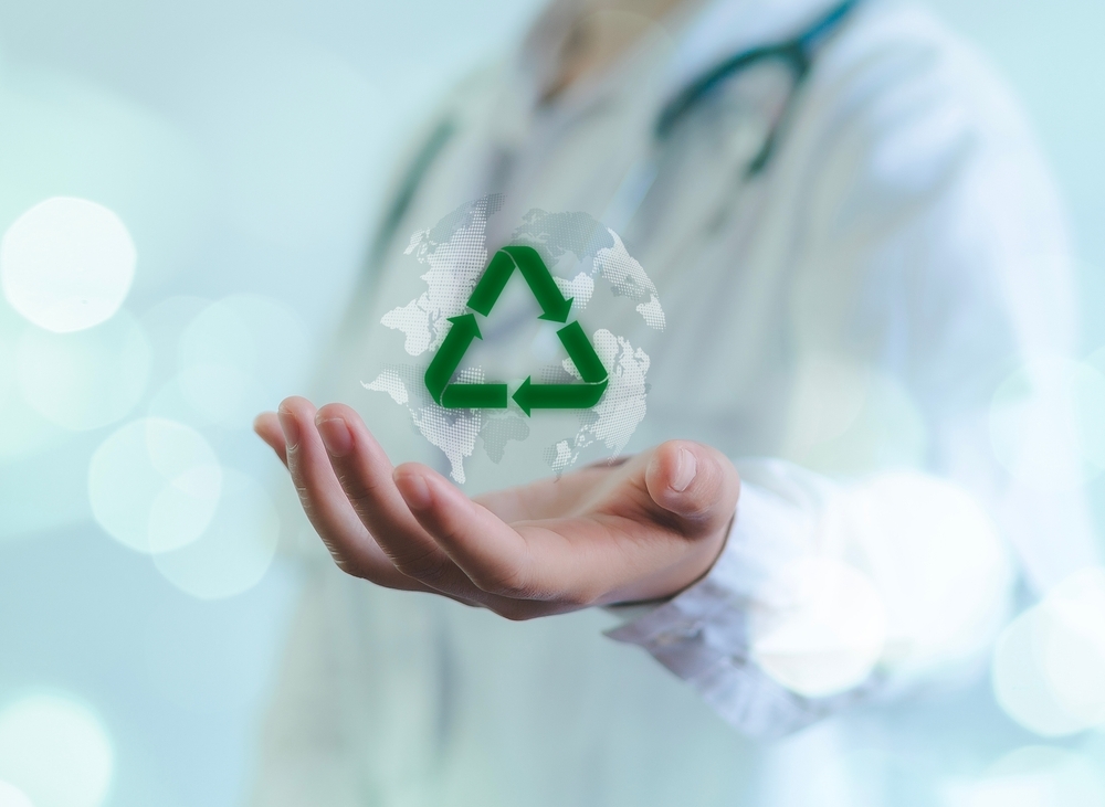 Person in white lab coat holding glowing holographic recycle sign, signifying medical personnel or high tech healthcare concept.